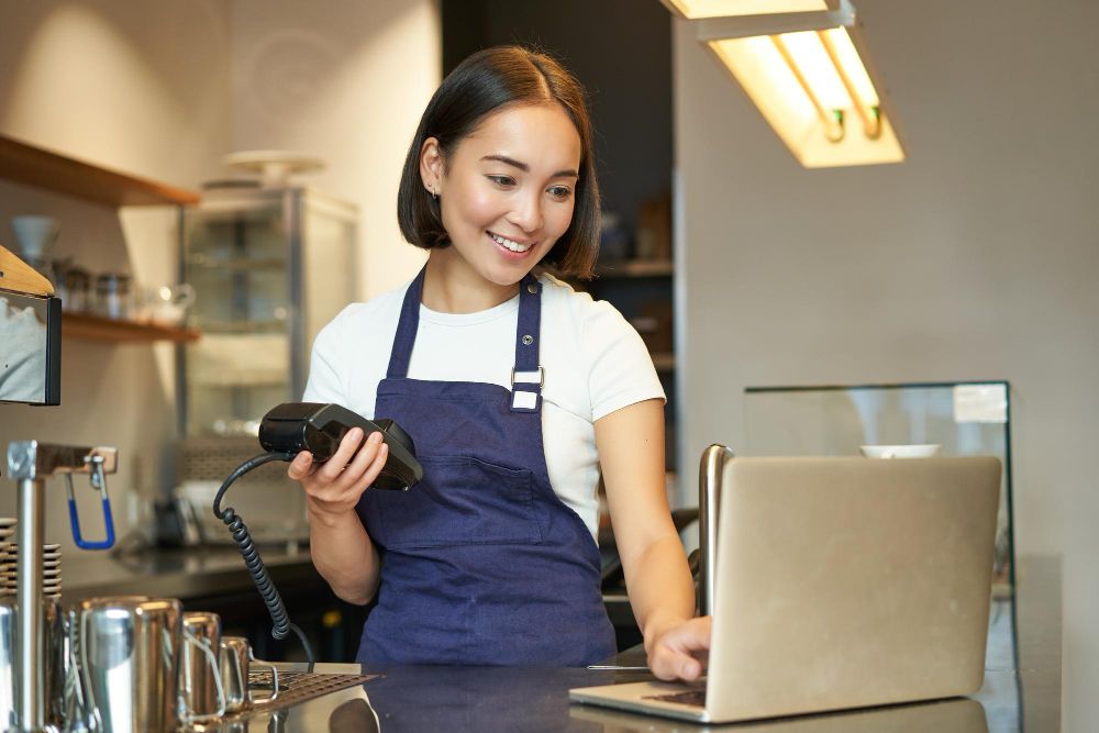 Kasir restoran yang ramah sedang memproses pembayaran non-tunai dengan cepat menggunakan aplikasi kasir modern di tablet